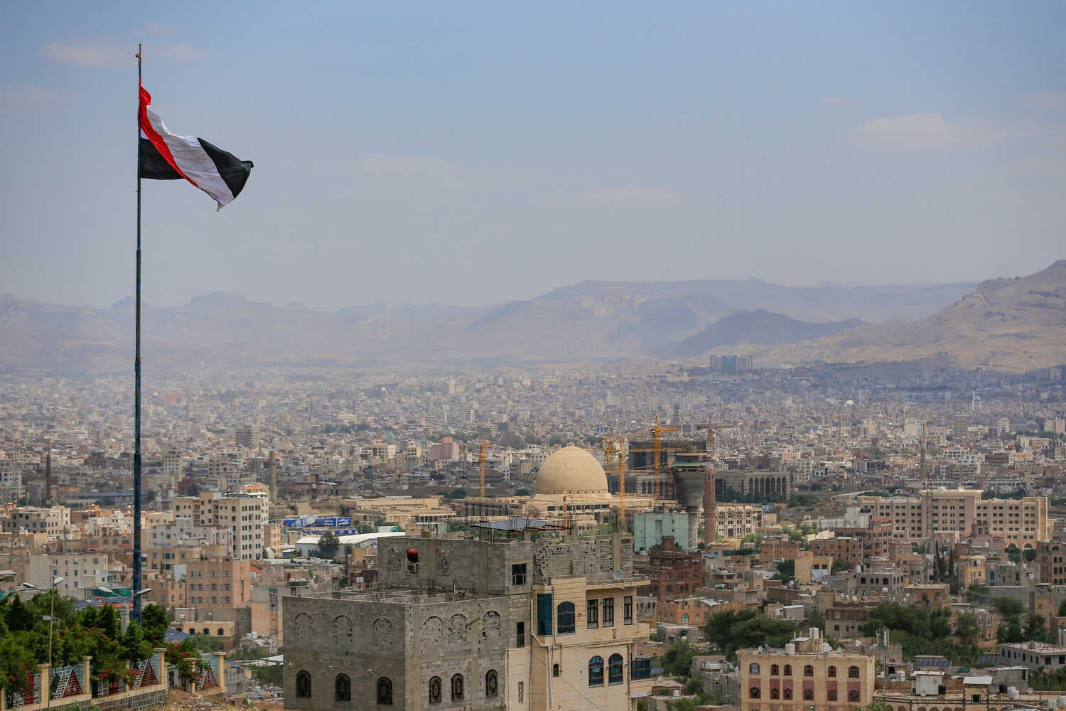 A large city scape of brown buildings with mountains in the background.