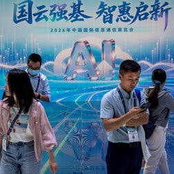 Several people stand in front of a large blue banner with the letters “AI” prominently displayed.